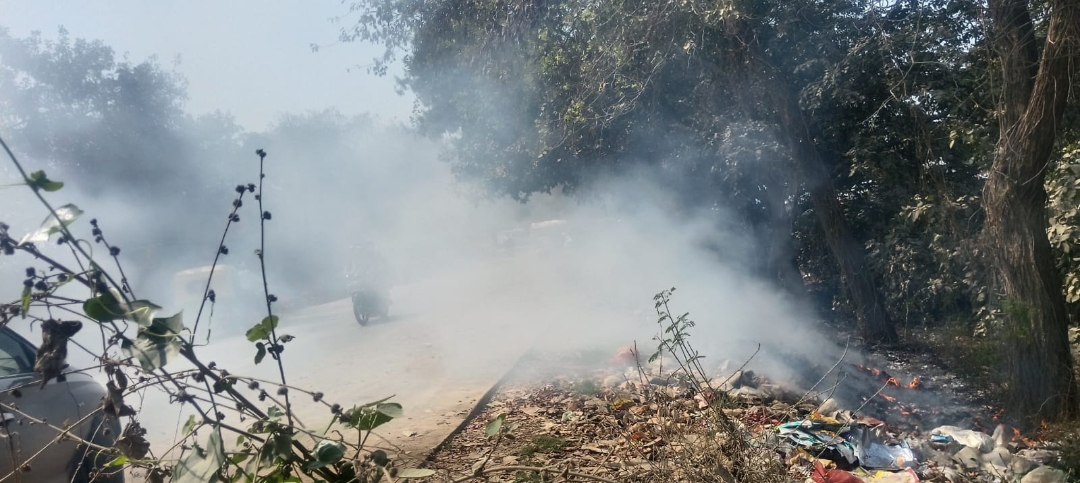 एयरपोर्ट के पास कूड़े के ढेर में लगाई गई आग, धुएं से राहगीर और दुकानदार परेशान